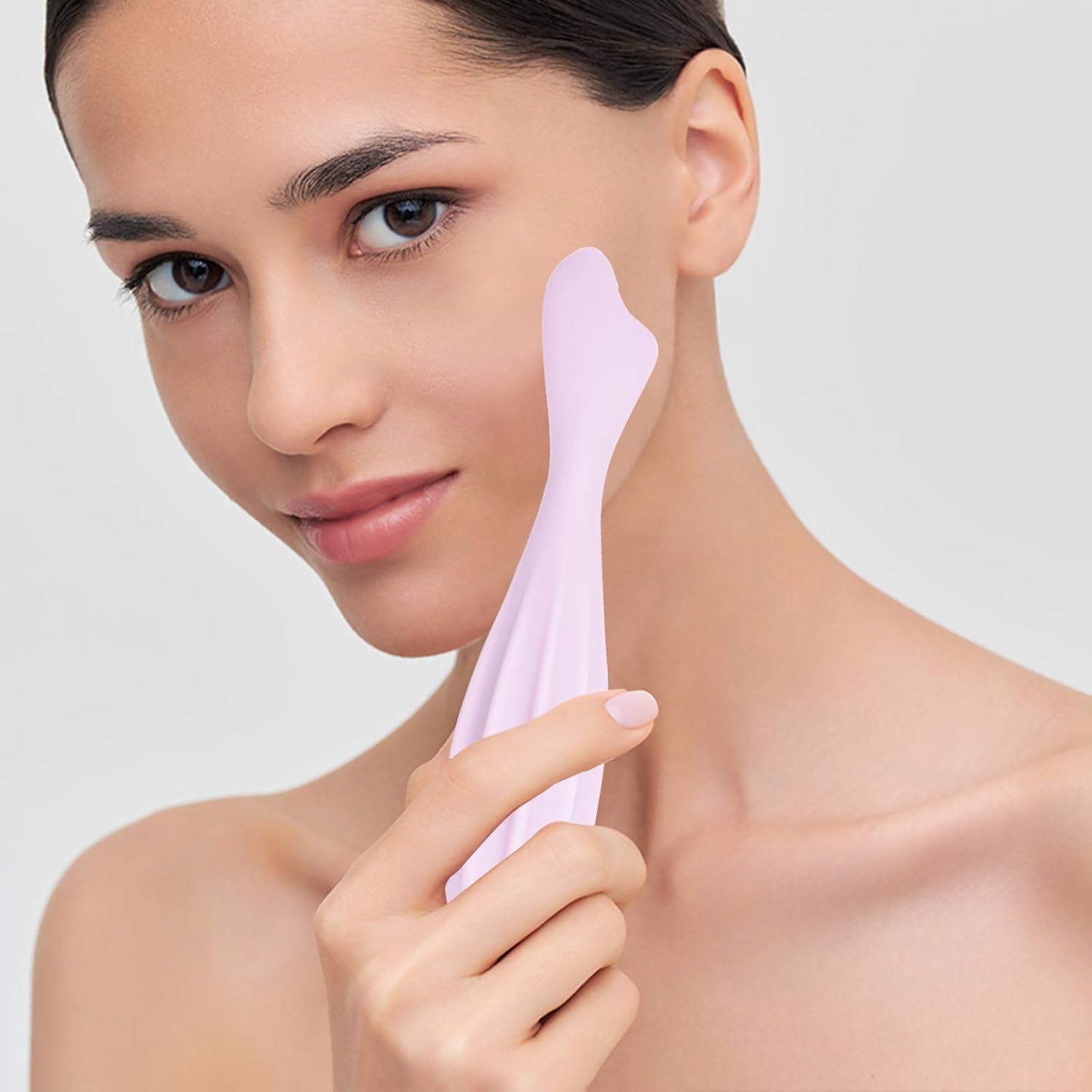 Model holding the Formora Muted Pink Face Roller close to her face, showcasing its ergonomic design and soft-touch silicone for a soothing skincare ritual.